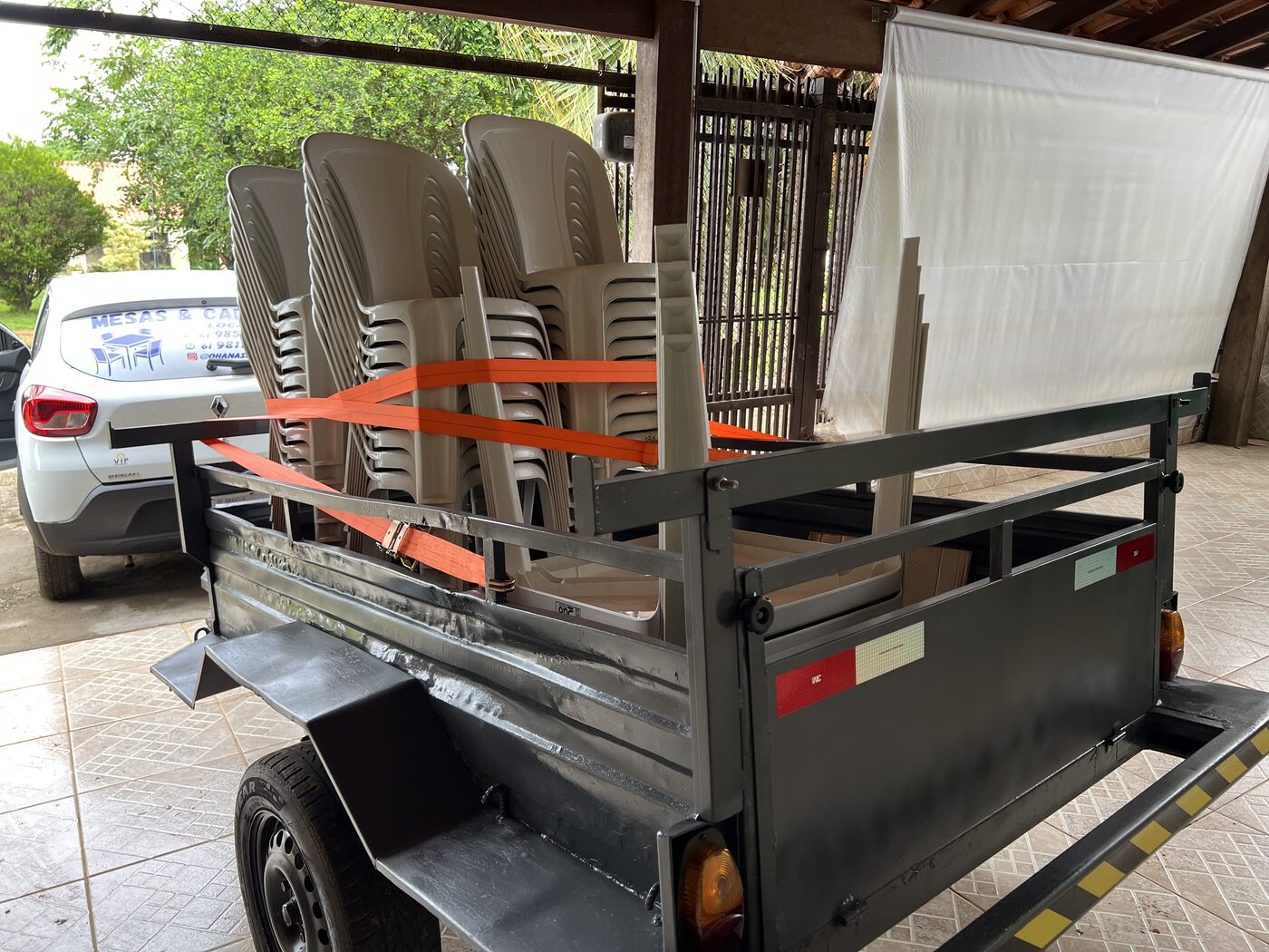 Carro adesivado com a carretinha carregada de mesas e cadeiras